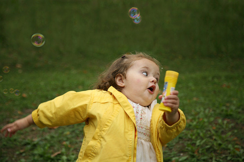 Young girl running away in a yellow jacket.